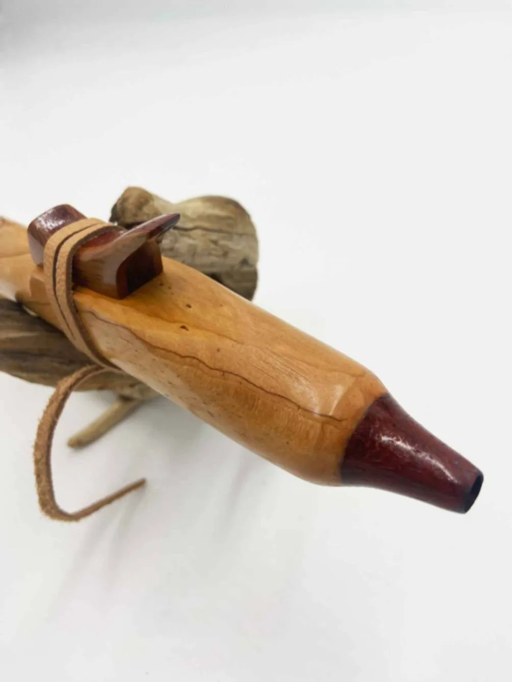 Vue de l’embouchure de la flûte amérindienne artisanale en position latérale, l’attache en cuir est visible sur le support