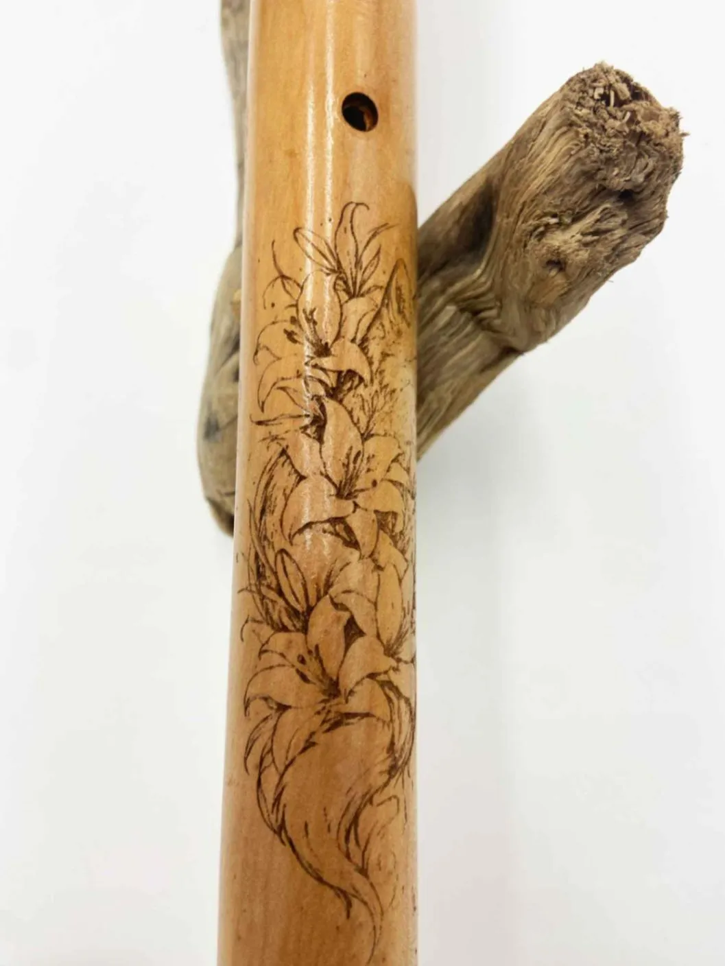 Gros plan sur la gravure latérale de la flûte amérindienne artisanale montrant un renard stylisé et motifs floraux pyrogravés