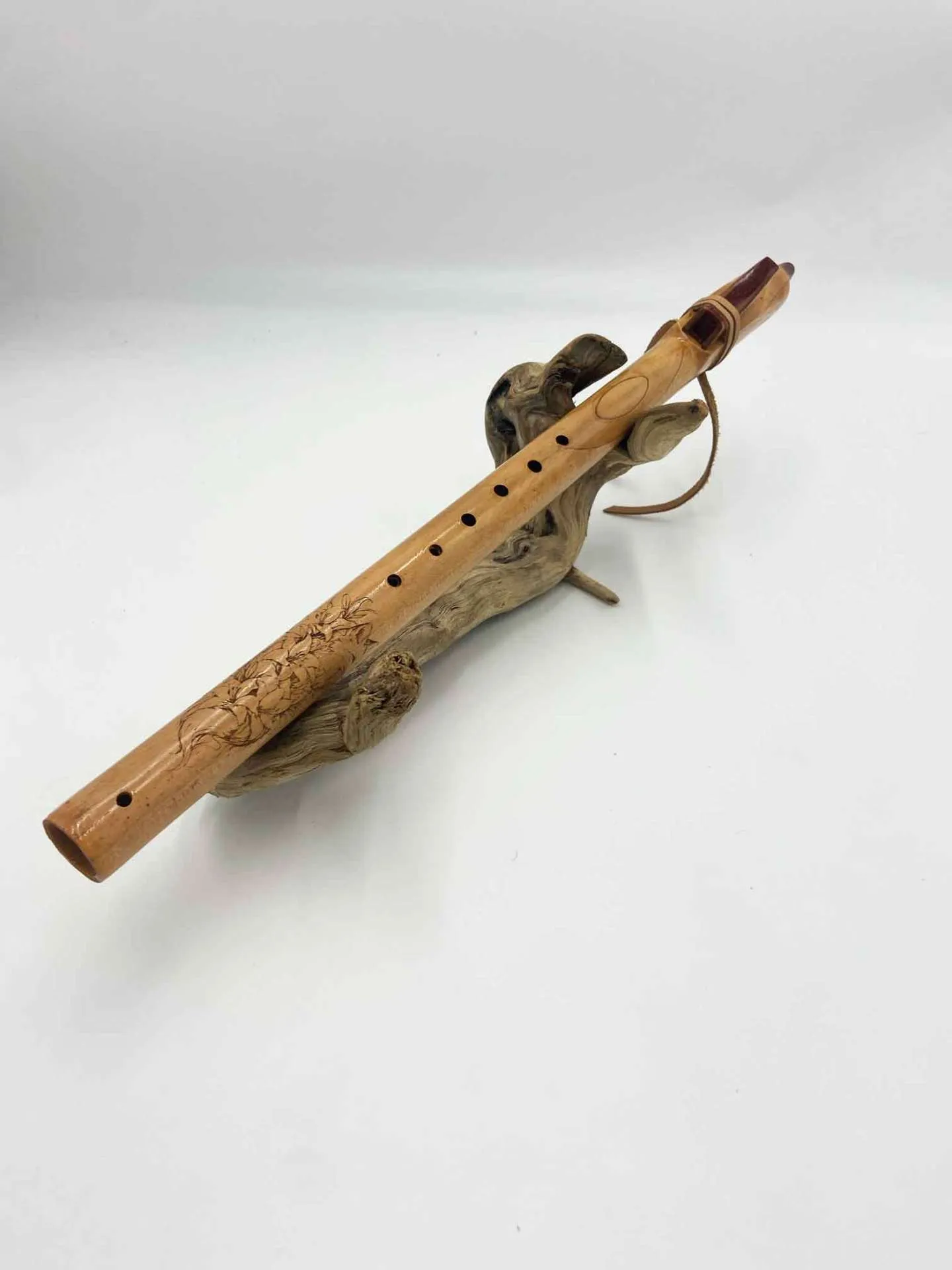 Vue rapprochée de la flûte amérindienne artisanale allongée sur un support, détails du pavillon et embouchure visibles